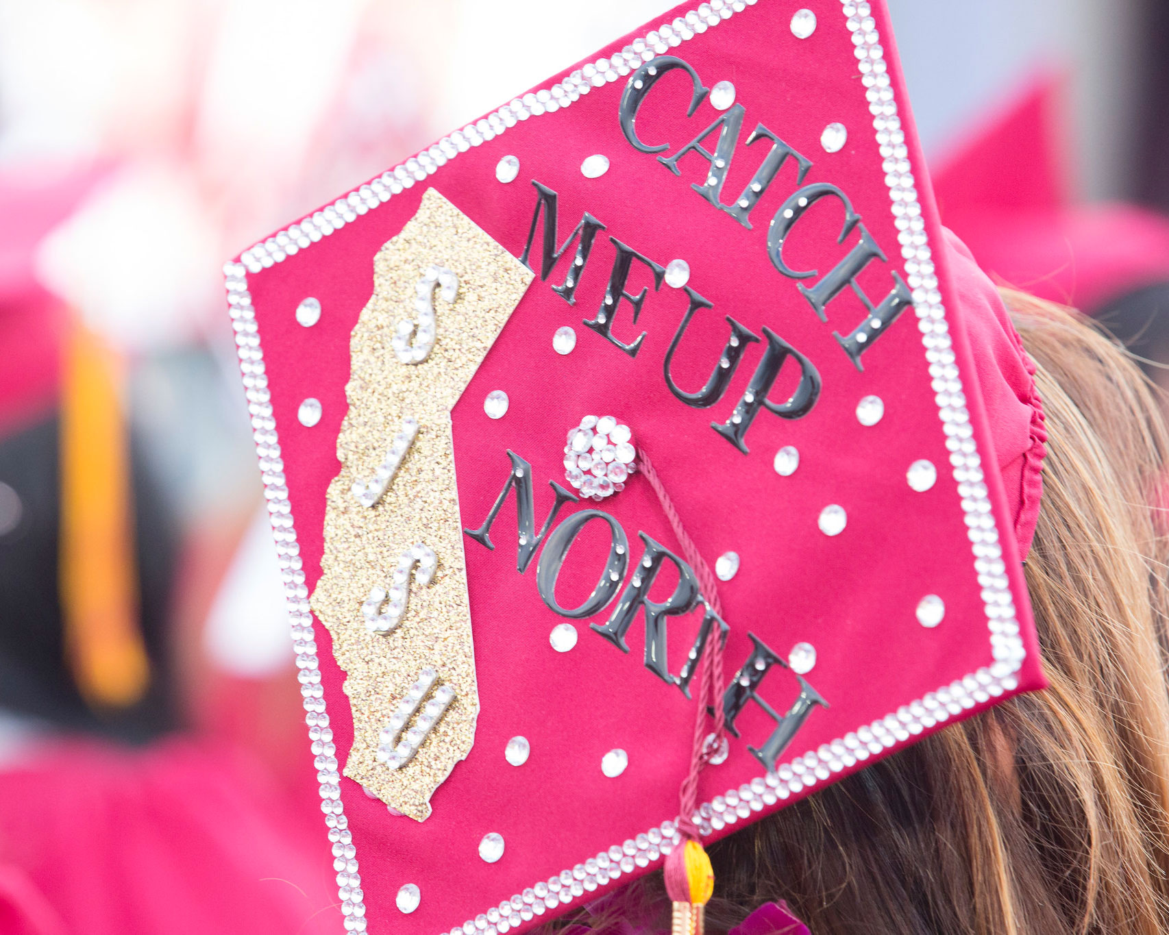 Student's graduation cap reads "Catch me up north, SJSU"